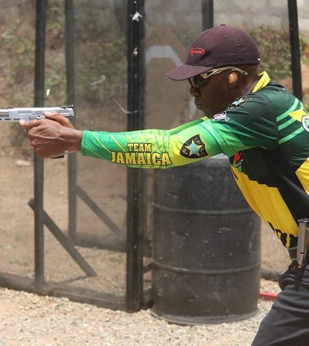 A competitor in Team Jamaica colours engaging a target with a pistol at full extension